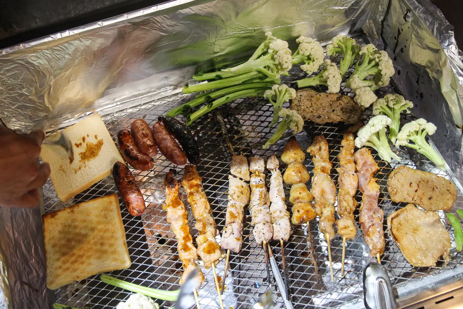 烤肉爐上正在燒烤吐司、香腸、肉串與蔬菜